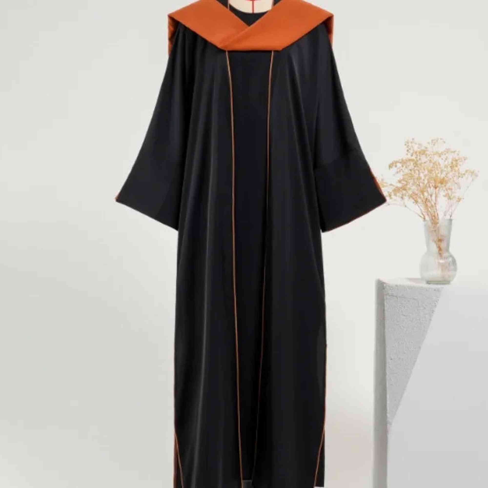 Elegant black modest gown with orange collar, displayed next to a vase, Zahra's Best fashion